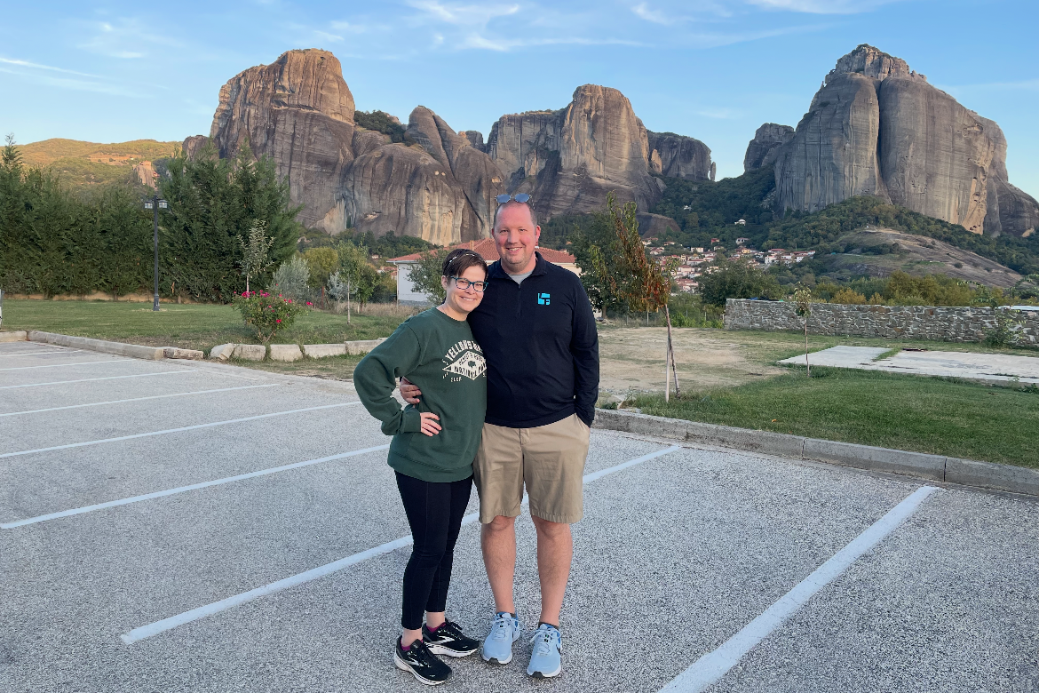 Two people standing in a parking lot with large rock formations in the background