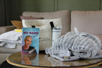 Book titled 'Diary of a No Name Girl' on a coffee table with folded blankets and a tumbler.