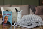 Book titled 'Diary of a No Name Girl' by Laura Stegall on a table with a blanket and other items.