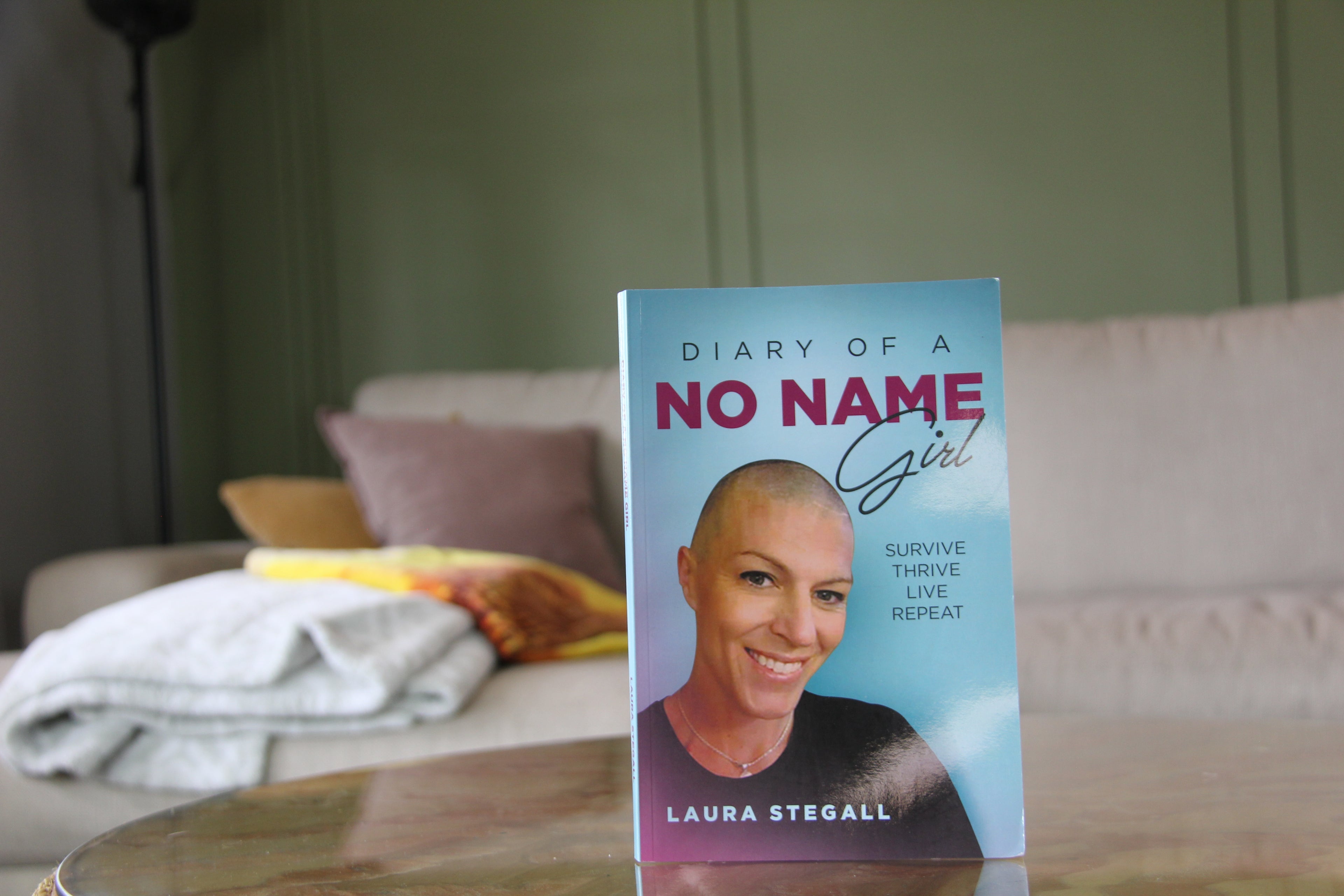 Book titled 'Diary of a No Name Girl' by Laura Stegall on a table with a blurred background